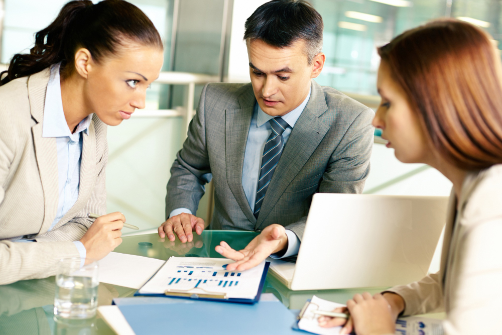 A man and woman dressed in business attire analyze a document, highlighting their partnership in Comprehensive Insurance Solutions.