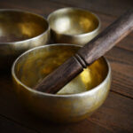 Tibetan handcrafted singing bowls with sticks on wooden background